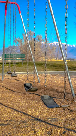 Vertical Swings at a playground casting shadows on the ground on a sunny day