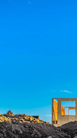 Vertical Framework of an unfinished house behind a mound of soil at a construction siteの写真素材