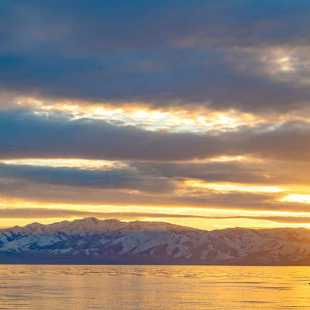 Square Scenic panorama of a lake and snow capped mountain under a striking cloudy sky