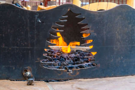 Close up of a black metal fire pit with an opening in the shape of a tree