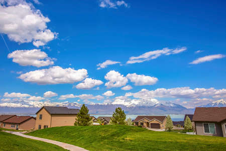 Pathway on a vast grassy terrain leading to the houses in front of a lake