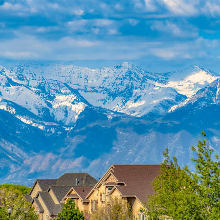 Frame Frame Square Houses and lush green trees with snow capped mountain in the backgroundの写真素材