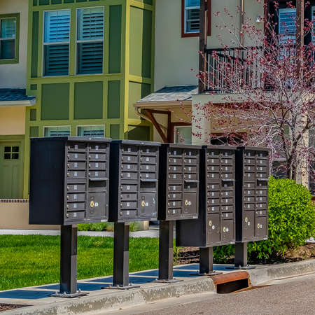 Frame Square Cluster mailboxes on the sidewalk in front of houses viewed on a sunny day