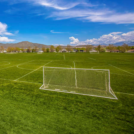 Frame Square Panorama of a soccer field with houses and mountain in the distance