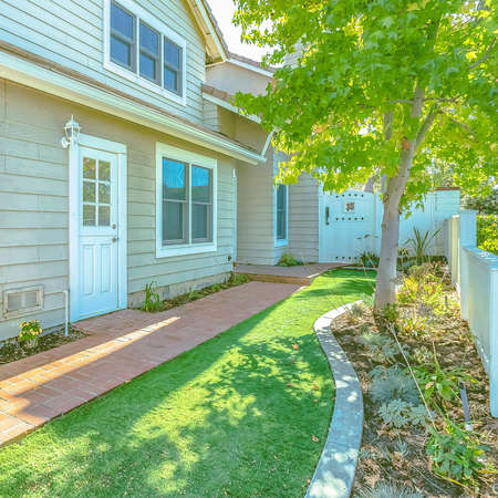 Square Backyard of a home with brick pathway and rich green lawn viewed on a sunny day