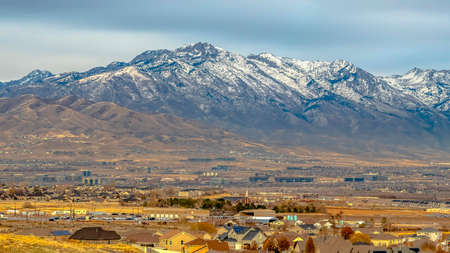 Panorama Panorama of a snow capped mountain towering over houses in the vast valleyの写真素材