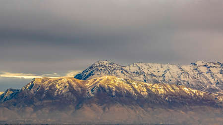 Panorama Panorama of a majestic mountain covered with snow and illuminated by sunlightの写真素材