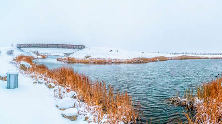 Panorama frame Panorama of a rippling lake with lush grasses on the snow covered shoreの写真素材