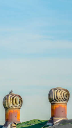 Panorama Green roof with metal turbine ventilator against cloudy pale blue skyの写真素材