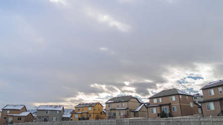 Panorama Facade of houses with white wooden fences under blue sky with thick cloudsの写真素材