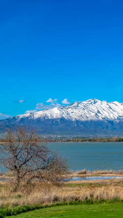 Panorama frame Panoramic view of a lake with brown grasses and sunlit field in the foregroundの写真素材
