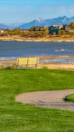 Panorama Trail and bench on a field overlooking the lake under blue sky on a sunny dayの写真素材