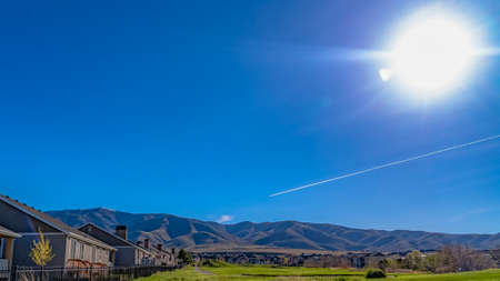 Panorama Houses on a lush grassy field under the blazing sun and vivid blue skyの写真素材
