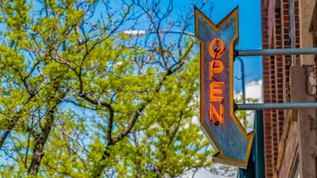 Panorama frame Open arrow sign on a building with vibrant trees and blue sky in the backgroundの写真素材