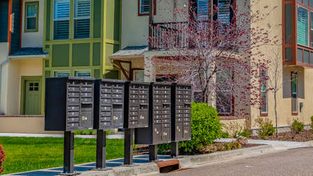 Panorama frame Cluster mailboxes on the sidewalk in front of houses viewed on a sunny dayの写真素材