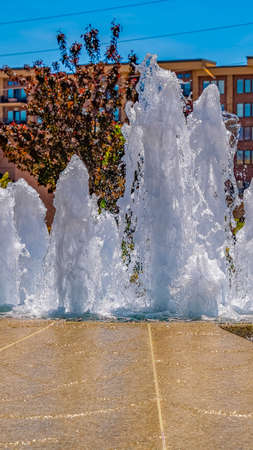 Panorama frame Fountain with sparkling water surging upwards against flowers and treesの写真素材