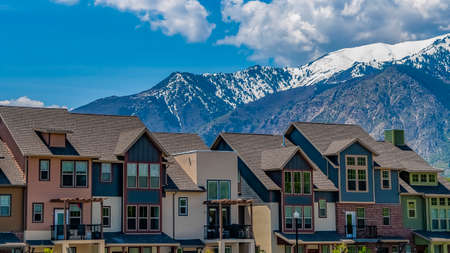 Panorama frame Exterior of stylish homes with an immense snow capped mountain in the backgroundの写真素材