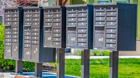Panorama Row of cluster mailboxes with numbered compartments on a sunlit sidewalkの写真素材