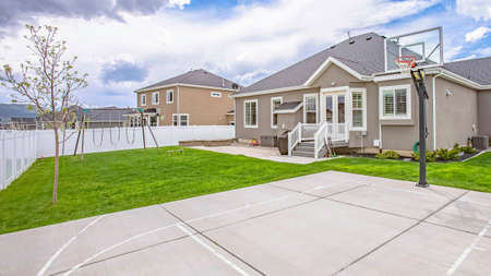 Panorama Basketball court and swings on the spacious yard of a single storey family homeの写真素材