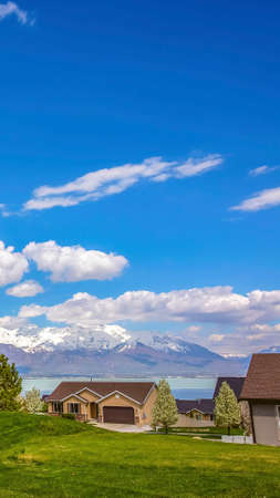 Panorama frame Pathway on a vast grassy terrain leading to the houses in front of a lakeの写真素材