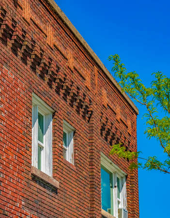 Close up of the exterior of a red brick building with bright foliage in frontの写真素材