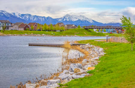 Wooden deck on a scenic lake with rocks and bright green grasses on the shoreの写真素材