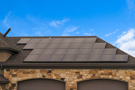 House with solar panels on the roof against blue sky with cloudsの写真素材