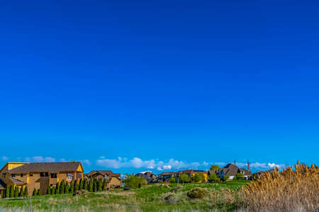 Houses on a vast grassy terrain with rich blue sky background on a sunny dayの写真素材