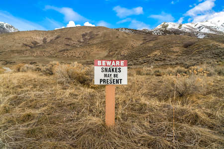 Sign that reads Beware Snakes May Be Present on a grassy mountainの写真素材