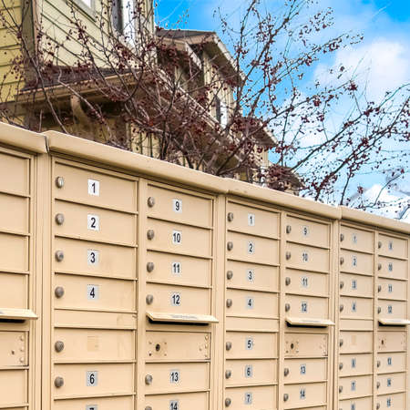 Square frame Residential mailboxes with numbered compartments on the side of a road. Homes, snow...