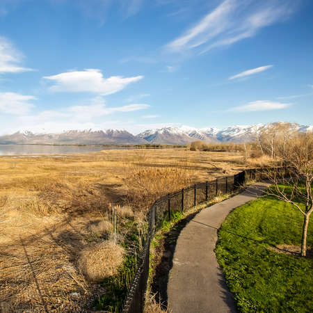 Square Paved pathway and fence along the shore of a lake with brown grassesの写真素材