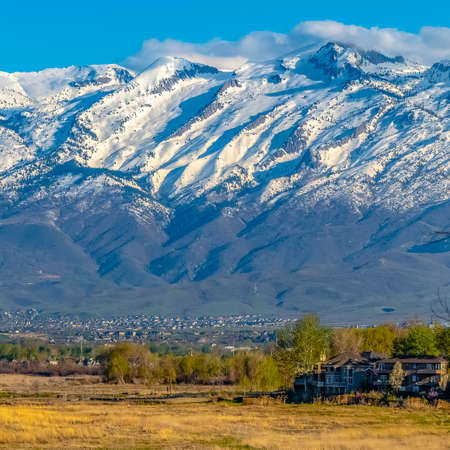 Square frame Striking snowy mountain towering over the valley under blue sky on a sunny dayの写真素材