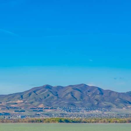 Square Mountain towering over a vast valley and lake under bright blue sky