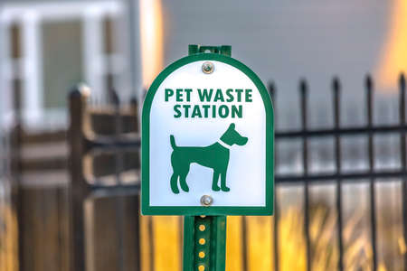 Close up of a Pet Waste Station with gate and building in the blurry background. The station provides pet owners a means to clean up after their dogs.の写真素材