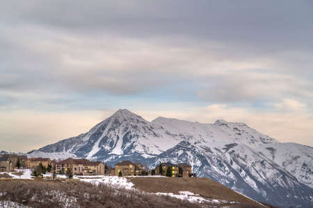 Homes with view of towering snow peaked mountain and overcast sky in winter
