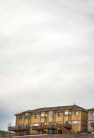 Homes with balconies and half hexagon shaped windows under overcast sky. The houses also have horizontal wall sidings and roofs with chimney pipes.の写真素材