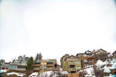 Multi storey homes with balconies built on a hill with fresh snow in winter. A vast sky filled with...