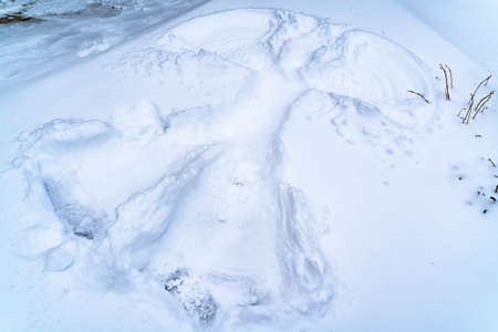 Close up view of a snow angel created on the ground covered with snow in winter. The design is made...