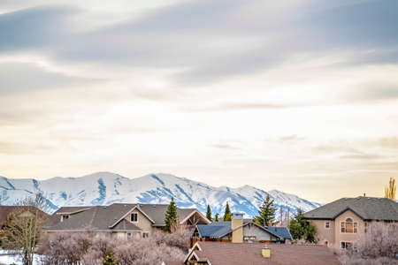 Neighborhood in winter with snow covered mountain and overcast sky background. The beautiful homes...