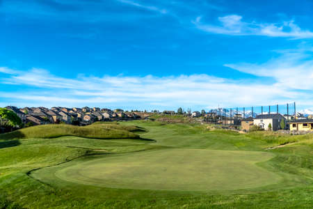 Golf course and homes under blue sky with clouds viewed on a sunny day. A mountain with snow covered peak can be seen in the distance.の写真素材