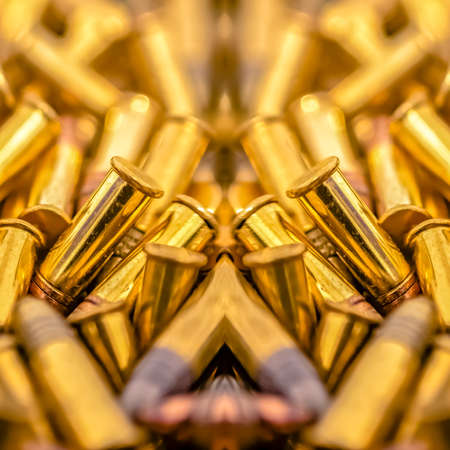 Pile of shiny bullets on an axis of symmetry. Geometric kaleidoscope pattern on mirrored axis of symmetry reflection. Colorful shapes as a wallpaper for advertising background or backdrop.の写真素材