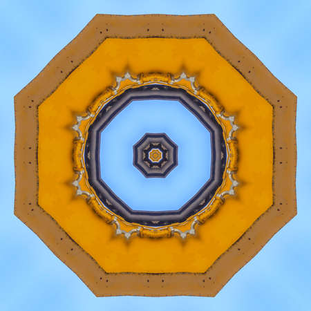 Abstract emlem made from yellow tractor arm. Geometric kaleidoscope pattern on mirrored axis of symmetry reflection. Colorful shapes as a wallpaper for advertising background or backdrop.の写真素材