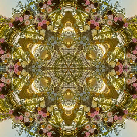 Flowers arranged into a geometric shape with many different colors photographed in California. Geometric kaleidoscope pattern on mirrored axis of symmetry reflection. Colorful shapes as a wallpaper for advertising background or backdrop.の写真素材