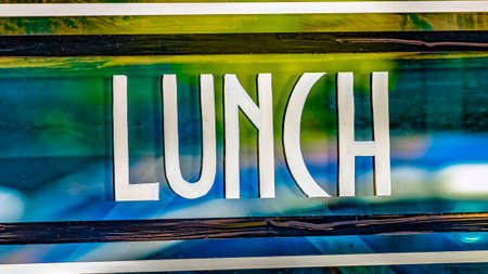 Panorama Close up view of a Lunch sign against the glass wall of a restaurant. The glossy glass surface reflects vehicles and buildings outdoor.の写真素材