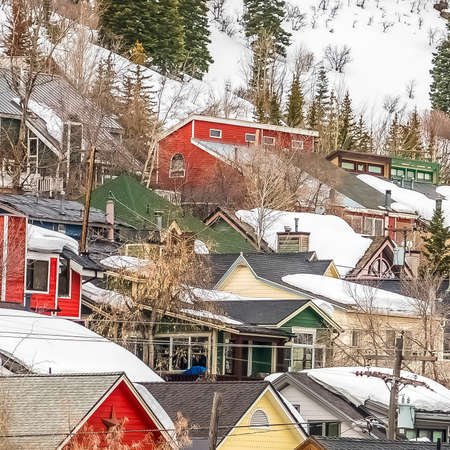 Square Houses with colorful walls built on a mountain covered with snow in winter. Lush coniferous...