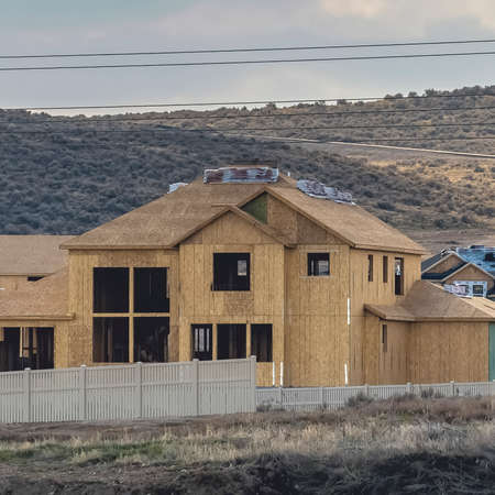 Square Homes un der construction against a hill with bushes and roadの写真素材