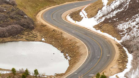 Panorama frame Highway curving through a mountain with snowy slope in winter