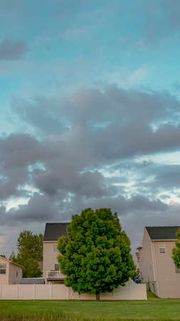 Vertical Scenic neighborhood with lovely homes and lush green trees under a cloudy sky. The houses have outdoor stairs leading to the balconies.の写真素材