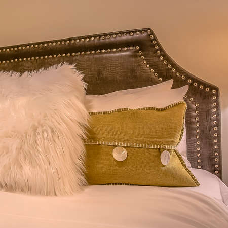 Square frame Bedroom interior with pillows against upholstered belgrave headboard of a bed. Wall...
