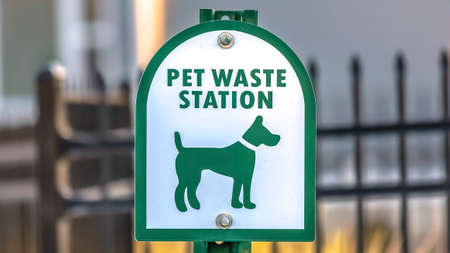 Panorama frame Close up of a Pet Waste Station with gate and building in the blurry background. The station provides pet owners a means to clean up after their dogs.の写真素材